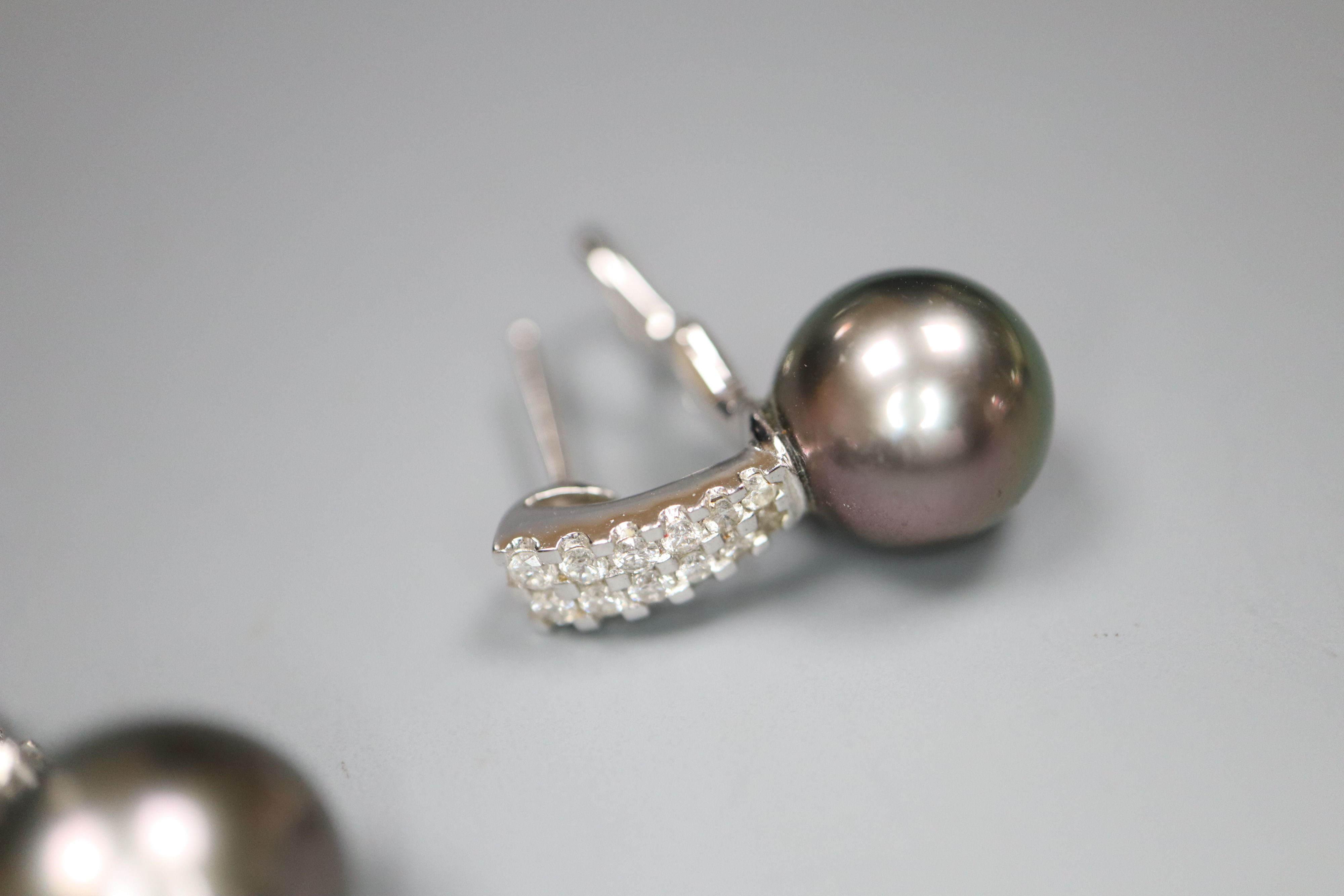 A modern 18k white metal , cultured Tahitian? pearl and diamond set pendant and pair of matching earrings.